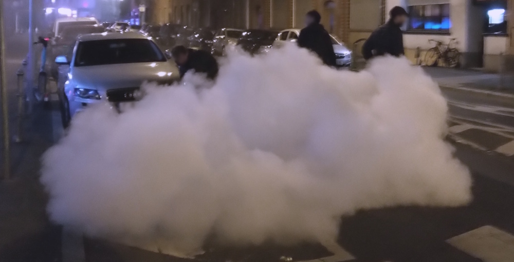 A small white cloud at the center of a city street at night