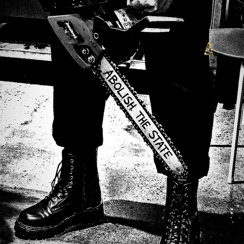 Black-and-white photo of a chainsaw with the words 'Abolish the state' writen on it