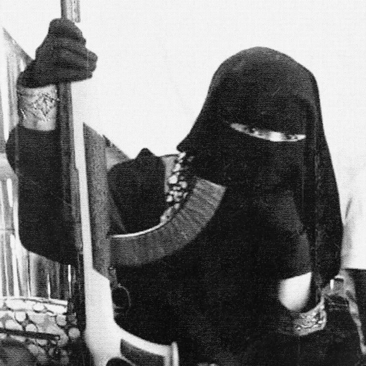 Black-and-white photo of a women wearing a burka and holding a kalashnikov