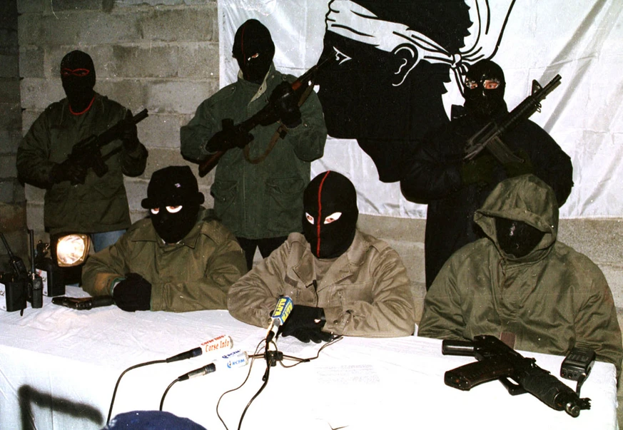 Photo of masked FLNC members holding a conference in a basement
