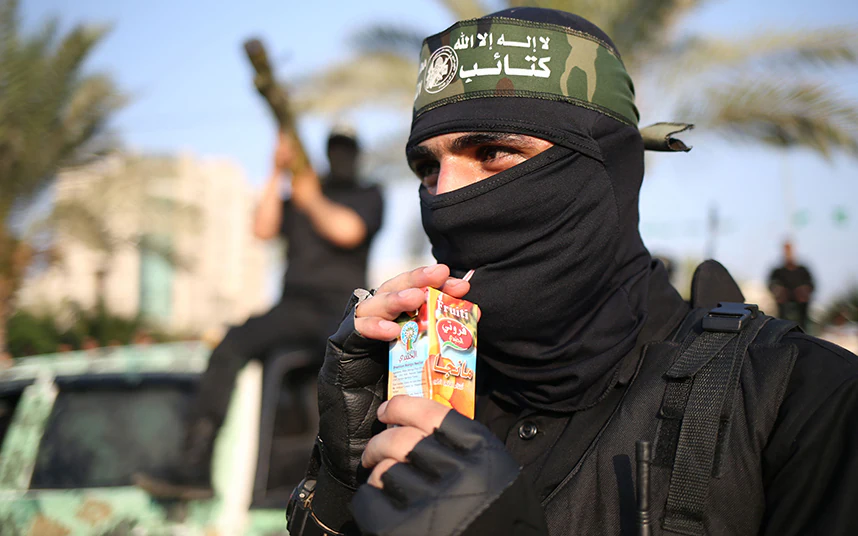 Photo of a masked Hamas fighter drinking from a juice box