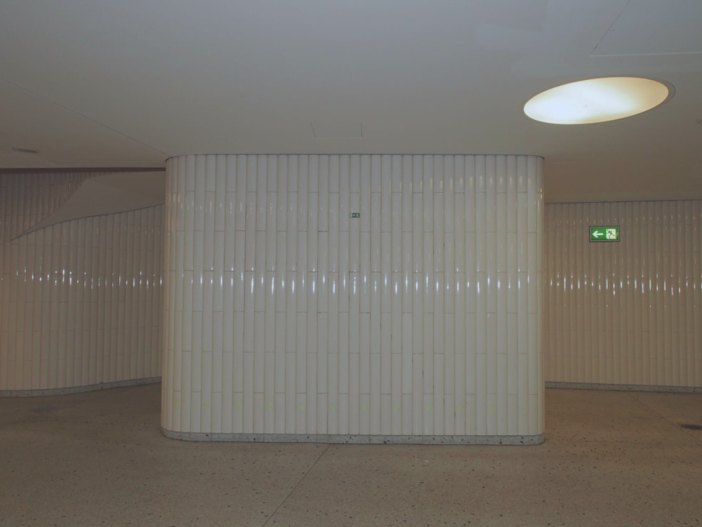 A wall of blank white tiles in some underground room
